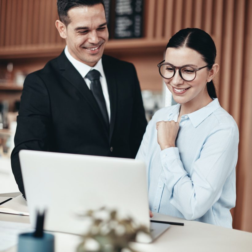 two-smiling-businesspeople-using-a-laptop-together-in-an-office.jpg